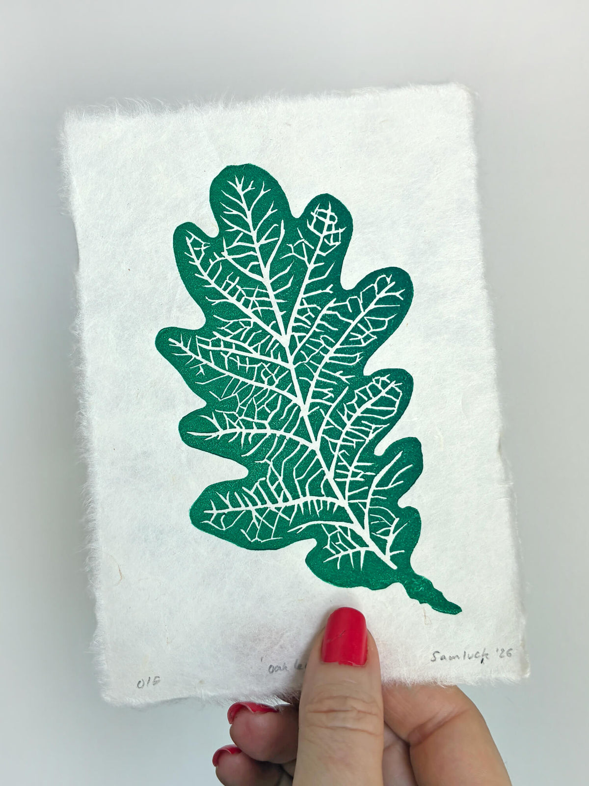 Hand holding a small botanical leaf linocut print of an oak leaf. Thoughtful gift for gardeners and nature lovers.