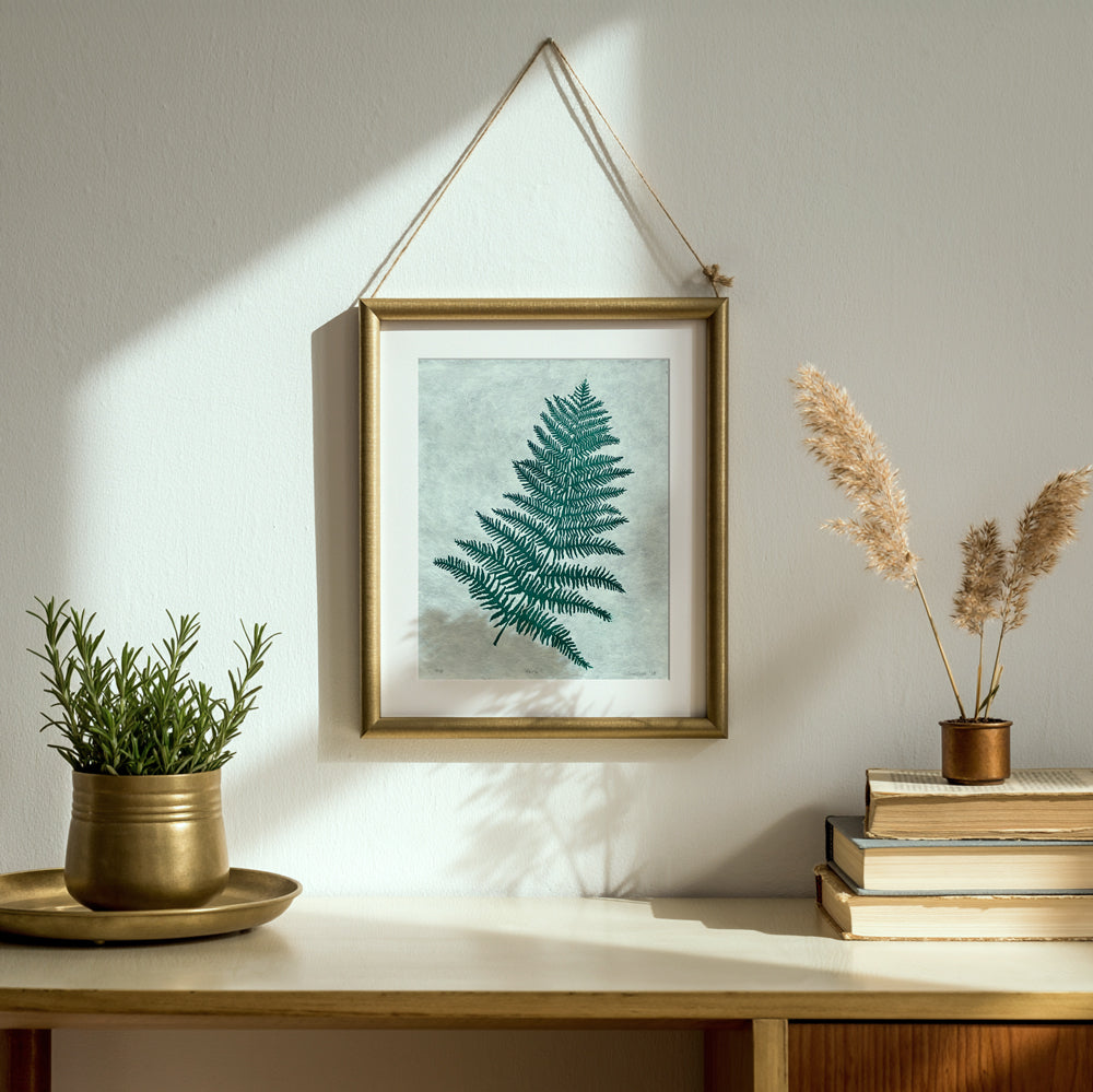 Handmade linocut print of a fern in a hanging brass frame, hand carved by UK artist, Sam Luck.