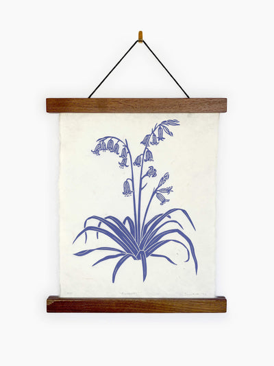 Image of a linocut print of British Bluebells in a poster frame hanging on a white wall.