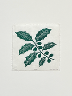 Handmade holly linocut print on handmade paper, view from above, isolated on white background hand printed by UK linocut artist Sam Luck