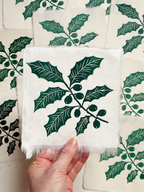 Handmade holly linocut print on handmade paper, held by hand, full view from above hand printed by UK linocut artist Sam Luck