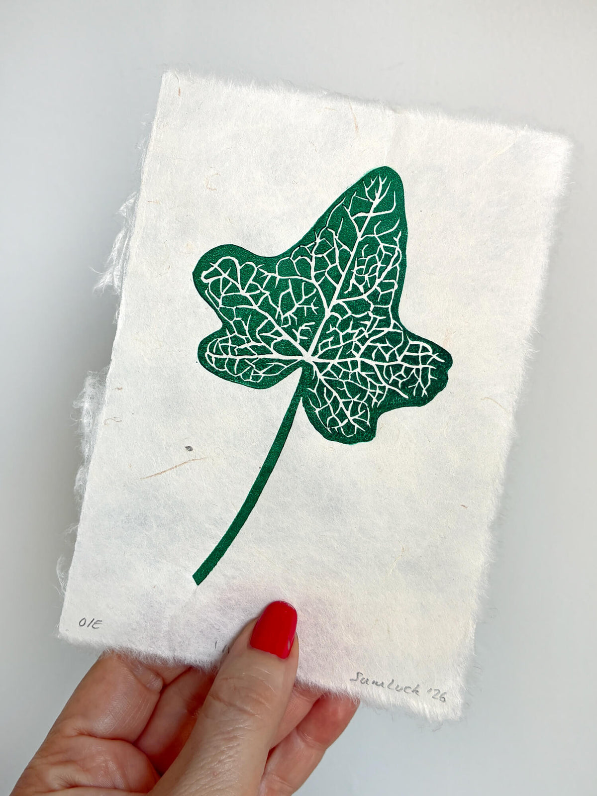 Hand holding a small botanical leaf linocut print of an ivy leaf. Thoughtful gift for gardeners and nature lovers.