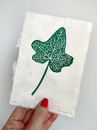 Hand holding a small botanical leaf linocut print of an ivy leaf. Thoughtful gift for gardeners and nature lovers.