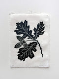 Handmade linocut botanical wall art print featuring oak leaves and acorns in green on an isolated background.