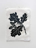 Handmade linocut botanical wall art print featuring oak leaves and acorns in green on an isolated background.