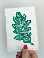 Hand holding a small botanical leaf linocut print of an oak leaf. Thoughtful gift for gardeners and nature lovers.