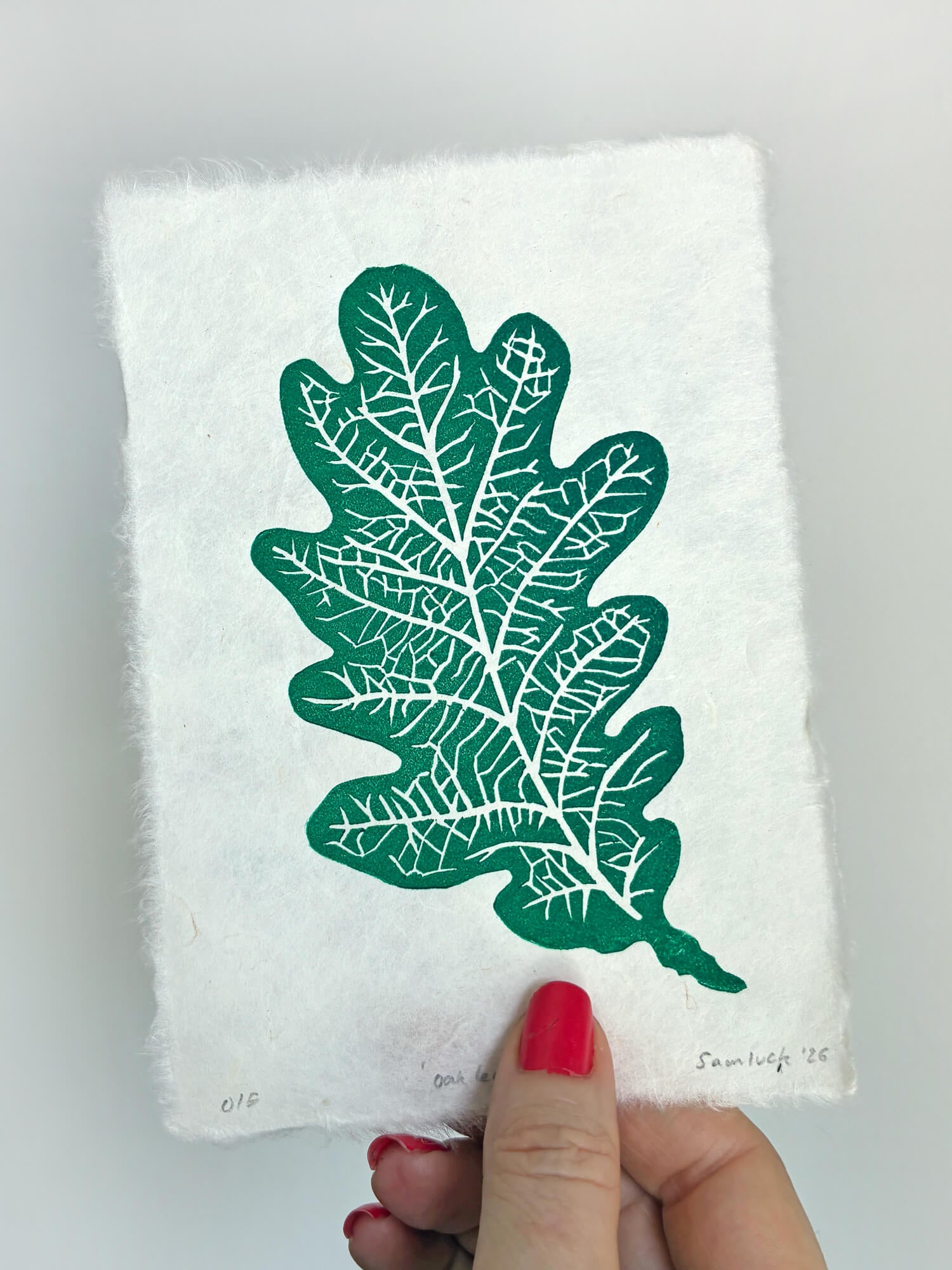 Hand holding a small botanical leaf linocut print of an oak leaf. Thoughtful gift for gardeners and nature lovers.