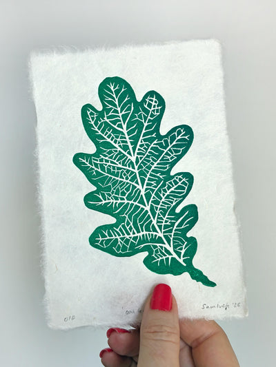 Hand holding a small botanical leaf linocut print of an oak leaf. Thoughtful gift for gardeners and nature lovers.