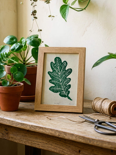 Small handmade oak leaf print in a wooden frame, on a gardening bench, with scissors and twine. 