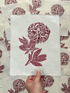 Hand holding a botanical wall art print of a red peony, by Sam Luck, linocut artist, UK.