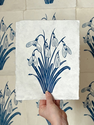 Handmade snowdrops linocut print on handmade paper, held by hand, full view from above hand printed by UK linocut artist Sam Luck