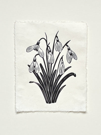Handmade snowdrops linocut print on handmade paper in black, full view from above on white background, hand printed by UK linocut artist Sam Luck