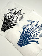 Handmade snowdrops linocut prints on handmade paper in black and blue ink, side view on white background, hand printed by UK linocut artist Sam Luck